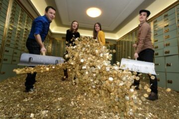 4 personnes munies de pelles, à l'intérieur d'un coffre-fort, soulèvent des tas de pièces d'or