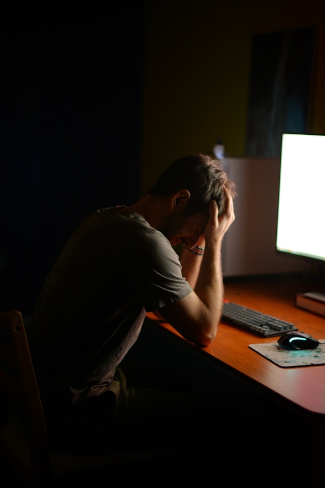 Un homme assis à son bureau dans une pièce sombre, face à un écran d'ordinateur et la tête entre les mains, visiblement inquiet ou angoissé.

Photo by LARAM on Unsplash