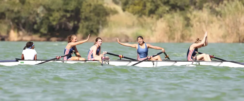 Une équipe d'aviron féminine qui semble victorieuse et soulagée après une course. Les coéquipières se congratulent entre elles.
